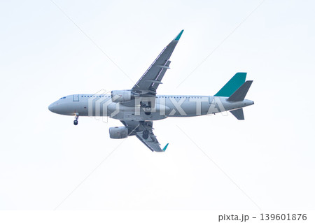 Narrow body passenger airplane flying at low altitude with landing gear deployed against a clean bright sky ideal for aviation and travel themes. 139601876