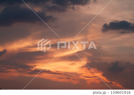 Vibrant sunset clouds glowing with rich orange and purple tones creating a dramatic atmospheric sky background with natural evening beauty. Vibrant sunset clouds glowing with rich orange and purple tones creating a dramatic atmospheric sky background with natural evening beauty. 139601916