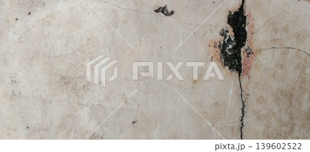 Close up of an old concrete wall texture with vertical cracks and dark mold stains on the surface. Close up of an old concrete wall texture with vertical cracks and dark mold stains on the surface. 139602522