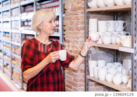 Elderly woman chooses pottery clay cup 139604129
