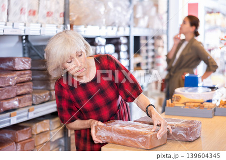 Elderly woman chooses pottery clay in shop Elderly woman chooses pottery clay in shop 139604345