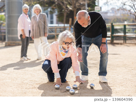 Elderly people analyzing the game results while playing petanca Elderly people analyzing the game results while playing petanca 139604390