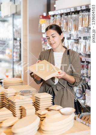 In pottery shop, positive woman chooses various wooden molds for future clay molding in her workshop In pottery shop, positive woman chooses various wooden molds for future clay molding in her workshop 139604503
