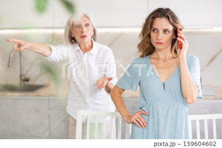Elderly mother kicks her out of house and yells at her adult daughter while she is talking on mobile phone Elderly mother kicks her out of house and yells at her adult daughter while she is talking on mobile phone 139604602
