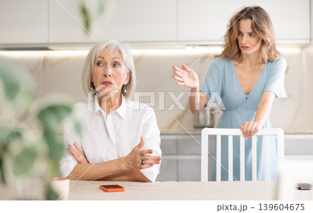 Adult woman quarreling with elderly woman in kitchen Adult woman quarreling with elderly woman in kitchen 139604675