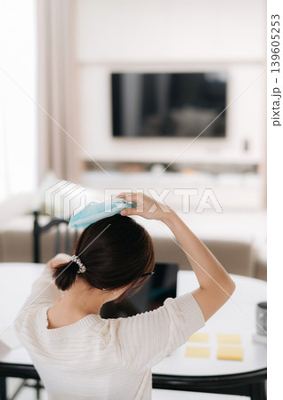 Sick asian woman suffering headache pain holding cold compress working with technology at home feeling stressed Sick asian woman suffering headache pain holding cold compress working with technology at home feeling stressed 139605253