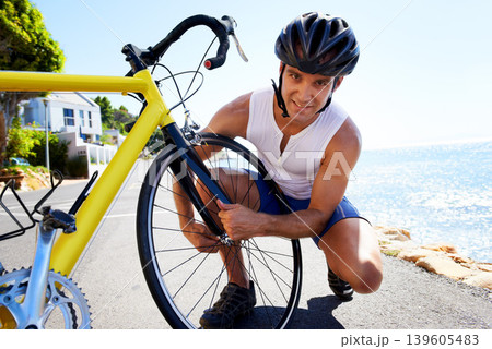 Man, portrait and wheel repair on road for safe cycling transport, performance or puncture. Male person, tyre and ocean for gear improvement or endurance for triathlon training, sport or practice 139605483