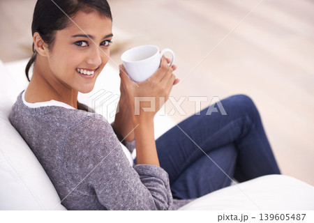 Coffee, living room and portrait of Indian woman on sofa for relaxing, comfortable and calm in home. Apartment, morning and happy person with mug on couch drinking hot beverage, tea and caffeine Coffee, living room and portrait of Indian woman on sofa for relaxing, comfortable and calm in home. Apartment, morning and happy person with mug on couch drinking hot beverage, tea and caffeine 139605487