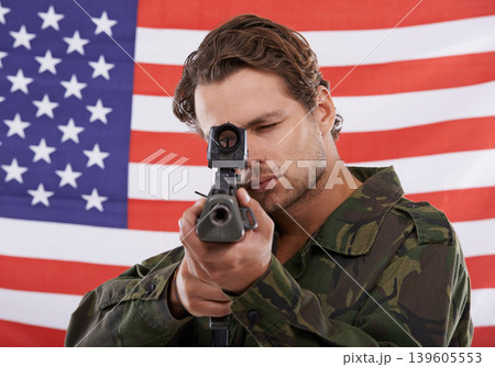 Military, aim and gun with portrait of man shooting in studio for war, conflict and patriotic. Army, surveillance and security with person on usa flag for soldier, battlefield and American veteran Military, aim and gun with portrait of man shooting in studio for war, conflict and patriotic. Army, surveillance and security with person on usa flag for soldier, battlefield and American veteran 139605553