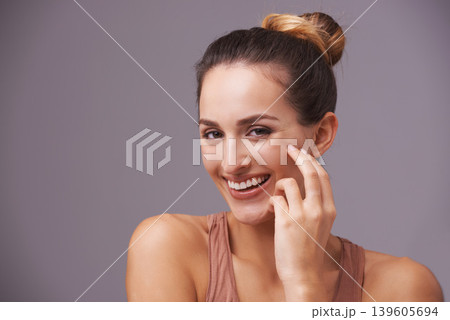 Portrait of happy woman, touching or beauty for cosmetics or skincare dermatology for facial glow. Results, natural face or confident model with smile, joy or wellness in studio on purple background Portrait of happy woman, touching or beauty for cosmetics or skincare dermatology for facial glow. Results, natural face or confident model with smile, joy or wellness in studio on purple background 139605694