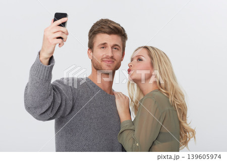 Selfie, happy and young couple in a studio for memory with love, care and sweet relationship. Smile, kiss and man and woman with picture photography for positive and good attitude by white background Selfie, happy and young couple in a studio for memory with love, care and sweet relationship. Smile, kiss and man and woman with picture photography for positive and good attitude by white background 139605974