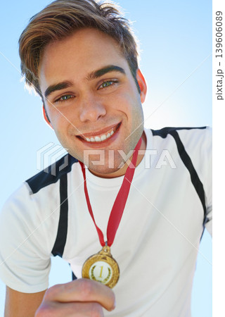 Winner, athlete and sports medal for achievement, success and portrait in running competition. Happy face of a young runner or man with red and gold award for contest or marathon on a blue sky 139606089