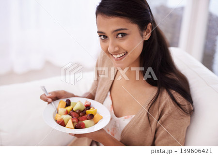 Happy woman, portrait and bowl of fruit in diet, nutrition or healthy snack on sofa at home. Face of young female person, nutritionist or vegan smile and eating breakfast for vitamin c, salad or meal 139606421