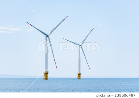 青い海の上に並んで立つ洋上風力発電の風車 139606497