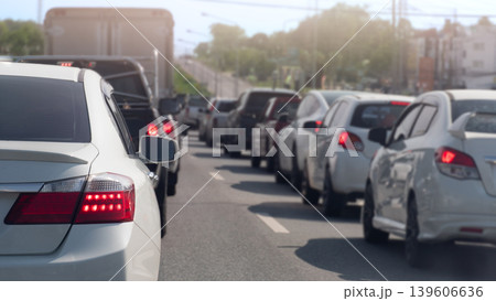 Long line of cars stuck in a traffic jam on a bright day. Perspective is from behind a white sedan. Showing the vast number of vehicles extending into the distance on a multi-lane road. 139606636