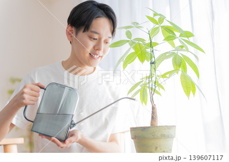 観葉植物にジョウロで水やりする若い男性 観葉植物にジョウロで水やりする若い男性 139607117
