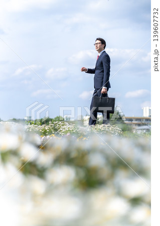 花畑で遠くを見つめるスーツの男性 139607732