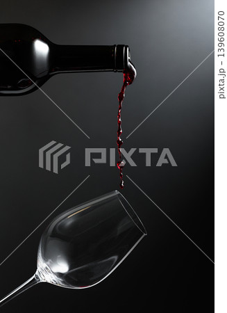 Red wine of rich color being poured from a bottle into a glass. Red wine of rich color being poured from a bottle into a glass. 139608070
