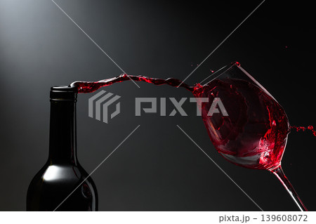 Red wine of rich color being poured from a bottle into a glass. Red wine of rich color being poured from a bottle into a glass. 139608072