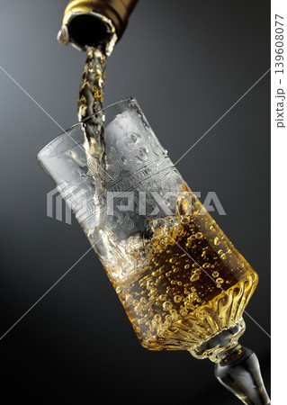 White sparkling wine is poured from a bottle into a glass. 139608077