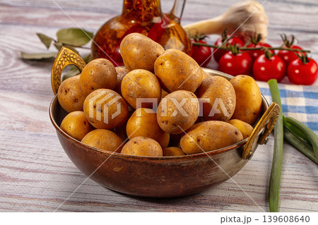 Bowl of small raw potatoes on wooden table with cooking ingredients Bowl of small raw potatoes on wooden table with cooking ingredients 139608640
