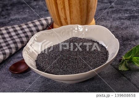 Poppy seeds in white ceramic bowl, culinary ingredient for baking on rustic dark background 139608658