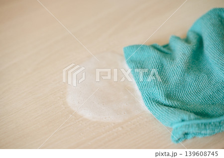 Hand wiping light-colored wooden surface with blue microfiber cloth, home cleaning and furniture care routine Hand wiping light-colored wooden surface with blue microfiber cloth, home cleaning and furniture care routine 139608745
