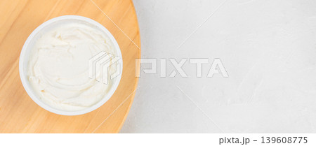 Cream cheese spread in plastic container on wooden board with copy space 139608775