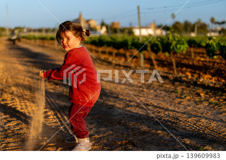 Girl playing outdoors with earth in a natural rural environment. Girl playing outdoors with earth in a natural rural environment. 139609983