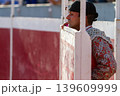 A telephoto of a concentrated bullfighter watches the bullfight from the sidelines	 139609999