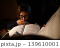 A stressed woman studying in a library for her final exams.	 139610001