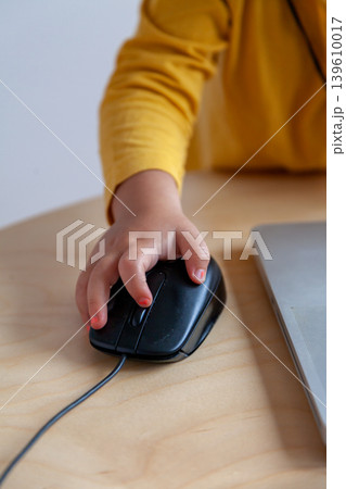 A hand of a child manipulates a laptop mouse, introducing concepts such as early access to social networks or teleworking. A hand of a child manipulates a laptop mouse, introducing concepts such as early access to social networks or teleworking. 139610017
