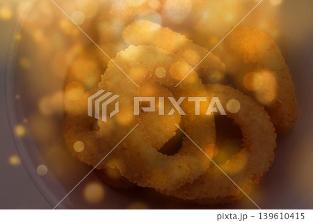 Golden Crispy Fried Onion Rings with Warm Bokeh.Delicious deep-fried onion rings in a bowl. Gourmet snack photography with glowing festive light overlays. 139610415