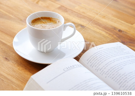 ページを開いた本(洋書)とコーヒーの入ったコーヒーカップで、コーヒーを飲みながら読書を楽しむイメージ ページを開いた本(洋書)とコーヒーの入ったコーヒーカップで、コーヒーを飲みながら読書を楽しむイメージ 139610538