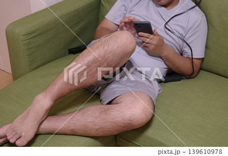 家のソファでスマホを見てくつろぐ男性 家のソファでスマホを見てくつろぐ男性 139610978