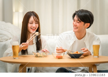 夜,食卓でおつまみを食べながら晩酌する若いアジア人カップル,夫婦 夜,食卓でおつまみを食べながら晩酌する若いアジア人カップル,夫婦 139611163