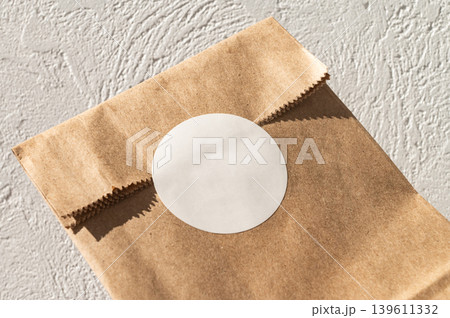 Brown paper bag with white circular sticker on textured surface Brown paper bag with white circular sticker on textured surface 139611332