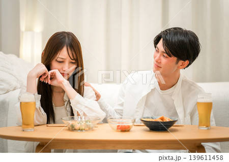 食卓で落ち込む女性と心配そうに声をかける男性 食卓で落ち込む女性と心配そうに声をかける男性 139611458