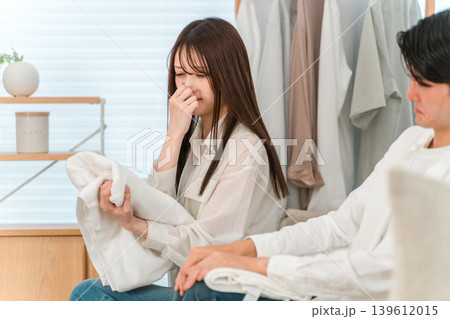 リビングでタオルを畳み洗濯物の生乾き臭に悩む夫婦,カップル リビングでタオルを畳み洗濯物の生乾き臭に悩む夫婦,カップル 139612015