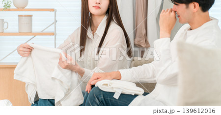 リビングでタオルを畳み洗濯物の生乾き臭に悩む夫婦,カップル 139612016
