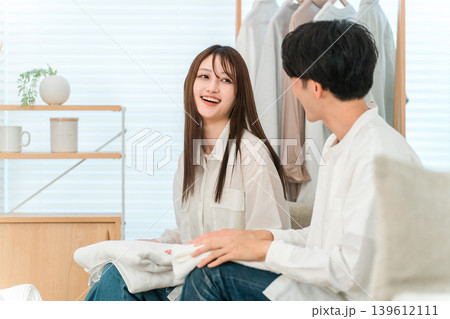 リビングで洗濯物を畳む笑顔の夫婦,カップル（家事参加,家事分担） 139612111
