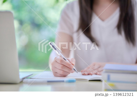 パソコンを見ながら勉強する若い女性 パソコンを見ながら勉強する若い女性 139612321