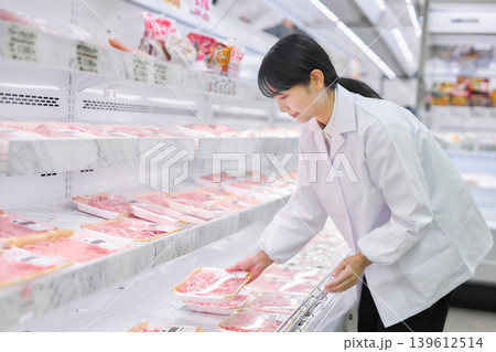 スーパーマーケットでお肉の品出しをする白衣の若い女性 139612514