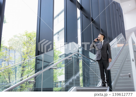 階段で電話するビジネスマン行動力とスピード感ある営業イメージ　髭のミドル男性 139612777
