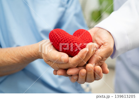 Asian woman doctor holding red heart with senior patient for health in hospital. 139613205