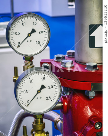 Pressure gauges show readings on a red system in a workshop setting with a blue background Pressure gauges show readings on a red system in a workshop setting with a blue background 139613210