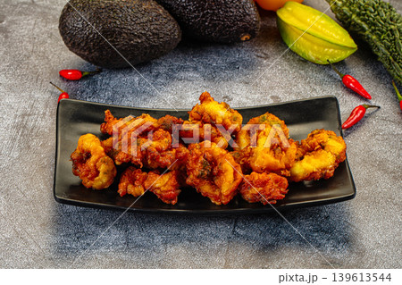 Crispy fried calamari rings appetizer on a plate with fresh chili and avocado. Crispy fried calamari rings appetizer on a plate with fresh chili and avocado. 139613544