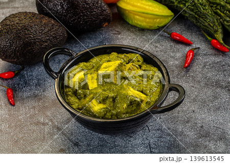 Palak Paneer, an Indian spinach and cottage cheese curry, served in a bowl with fresh vegetable ingredients. Palak Paneer, an Indian spinach and cottage cheese curry, served in a bowl with fresh vegetable ingredients. 139613545