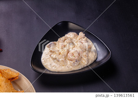 Gourmet creamy shrimp appetizer in a modern gray bowl with chili peppers on a dark background. 139613561