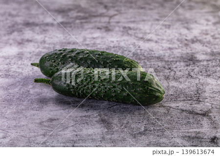 Two fresh green gherkin cucumbers on a grey textured stone background Two fresh green gherkin cucumbers on a grey textured stone background 139613674